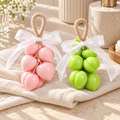 Duo Pêches Atelier Mousse : un savon rose et un savon vert sur corde, réunis sur un linge clair.