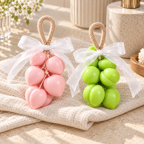 Duo Pêches Atelier Mousse : un savon rose et un savon vert sur corde, réunis sur un linge clair.